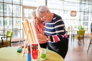 Vrijwilliger is met een bewoner aan het schilderen